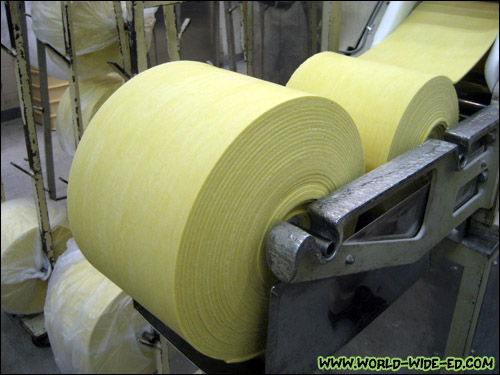 Large flour rolls feeding into the machine that cuts them into noodles
