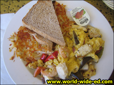 Eggs scrambled with roasted veggies & a tiger shrimp seafood mix, topped with hollandaise sauce & served with hash browns & toast for $10.25.